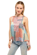 Woman wearing a colorful patterned sleeveless top and light blue jeans on a white background