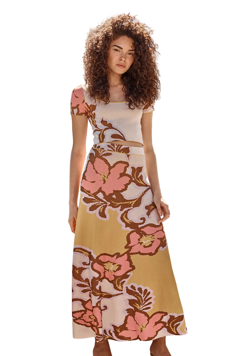 Woman wearing a floral dress standing outdoors with greenery in the background