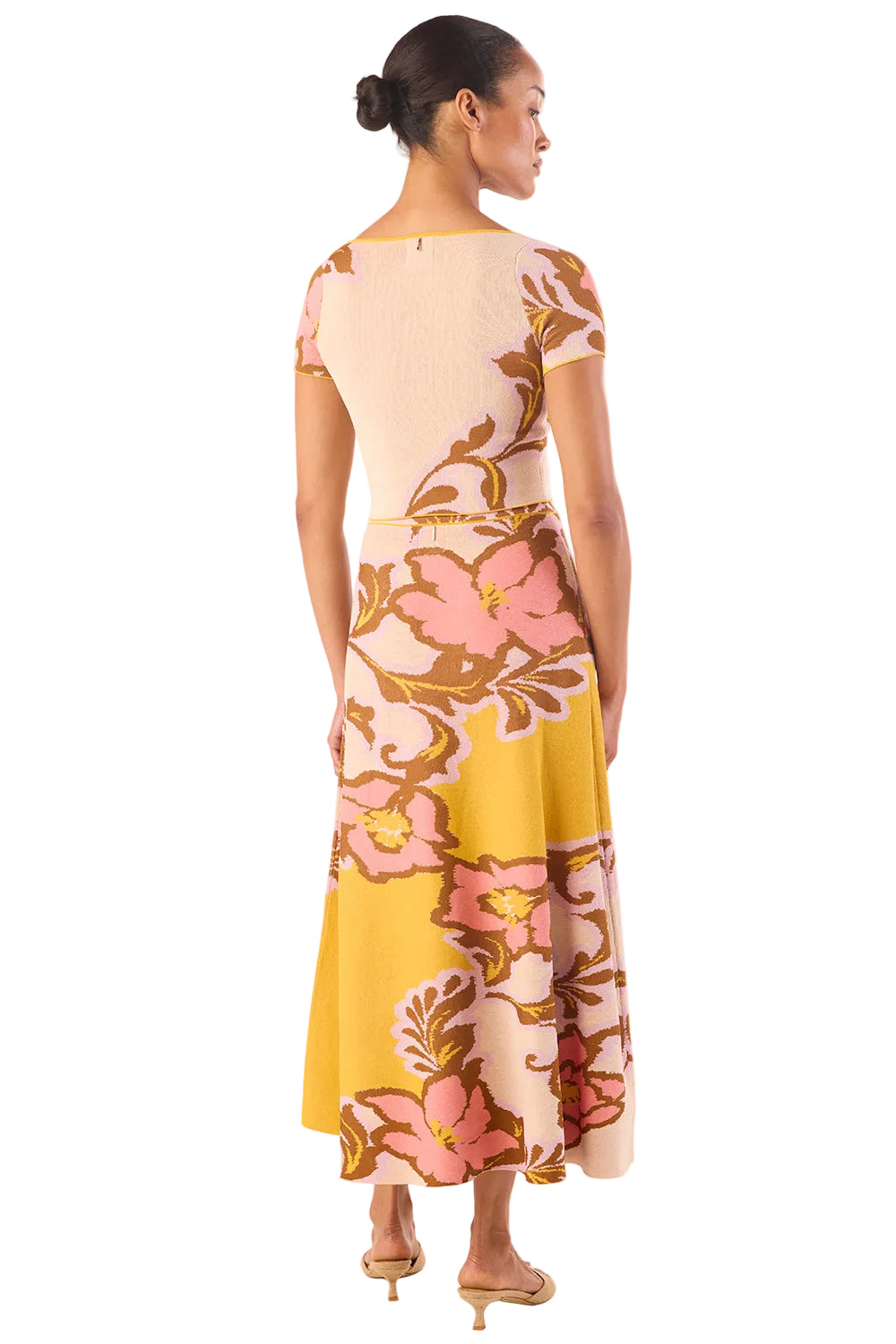 Woman wearing a floral dress with a yellow and pink pattern on a white background